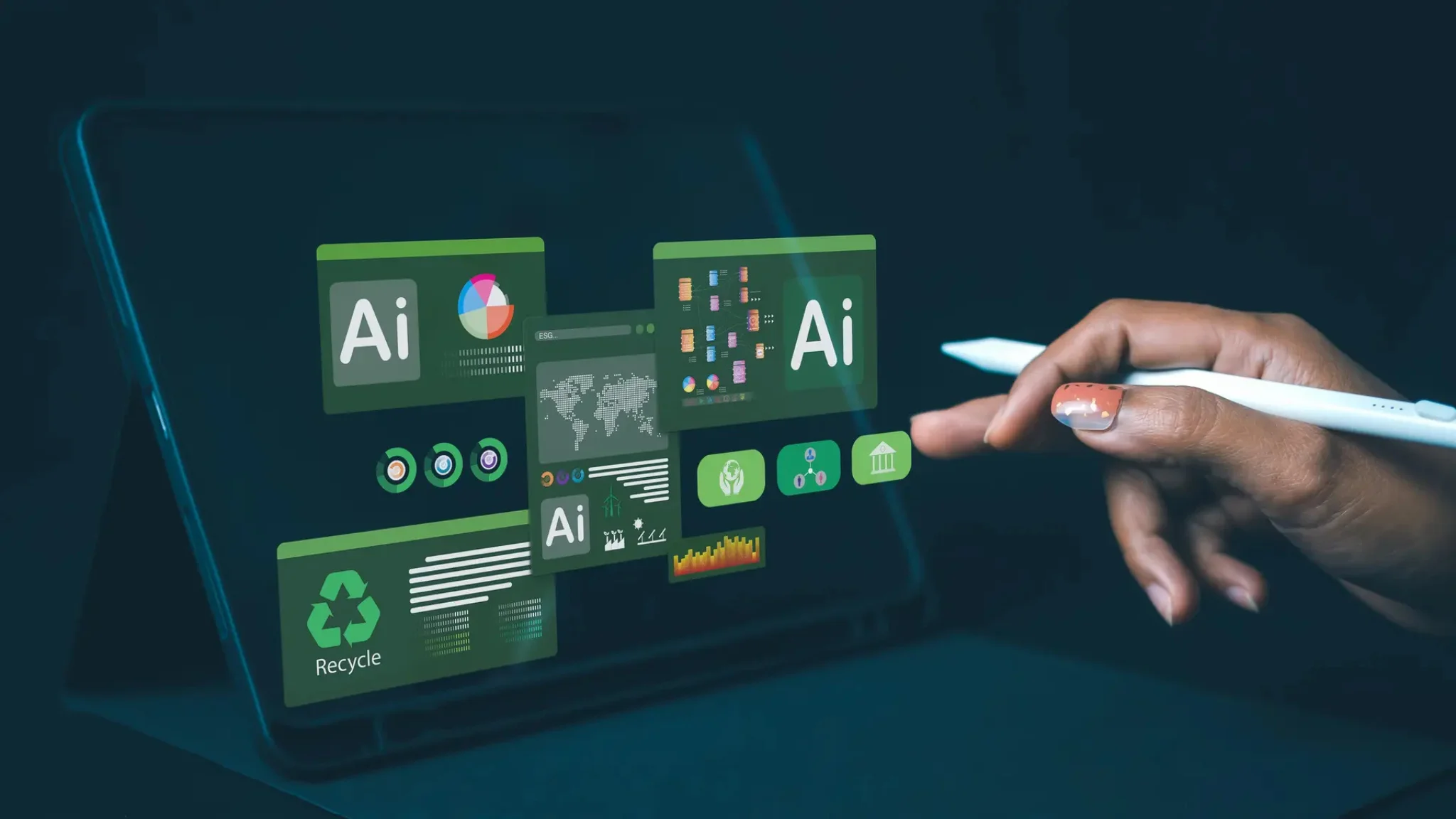 A person using a tablet with a pen, while a laptop screen displays various icons.