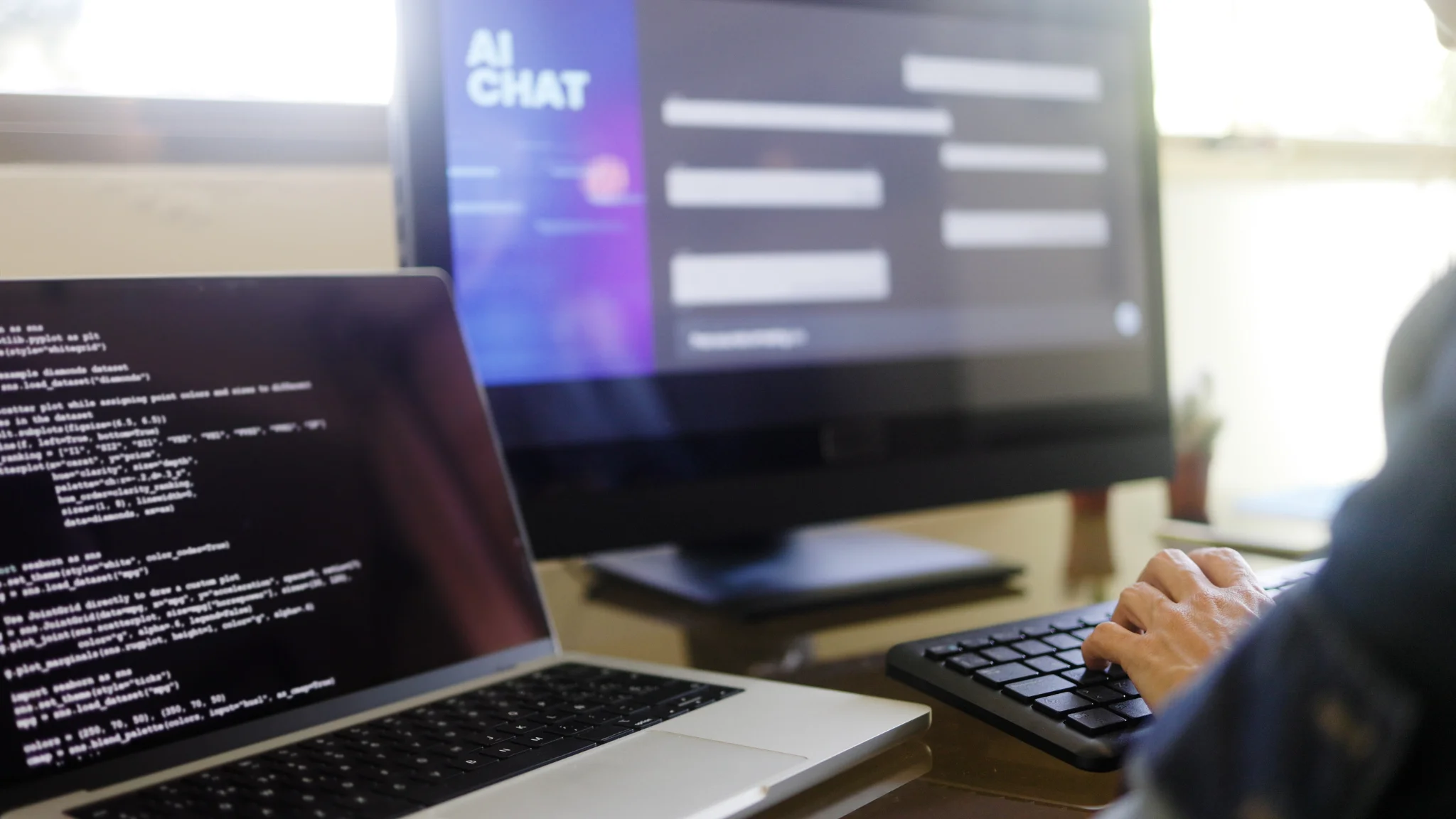 A person typing on a laptop, focused on their work with hands on the keyboard and a screen in view.