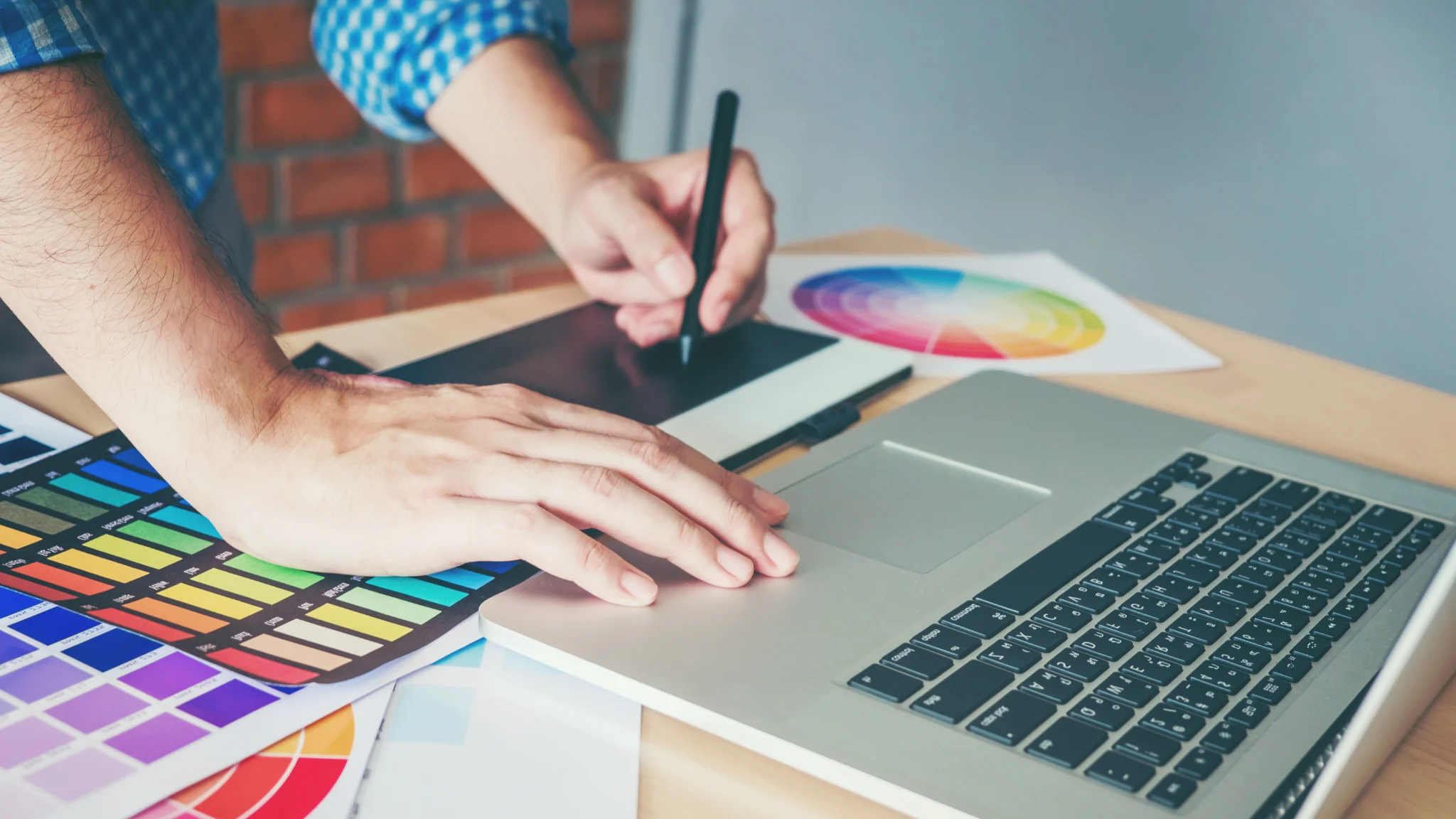 A person focused on a laptop, surrounded by a vibrant color palette, engaged in creative work.