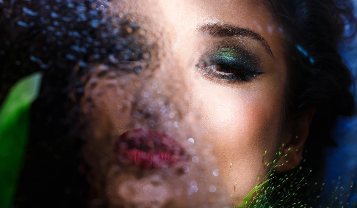 A woman with vibrant green makeup and striking green eyes, showcasing a bold and artistic look.
