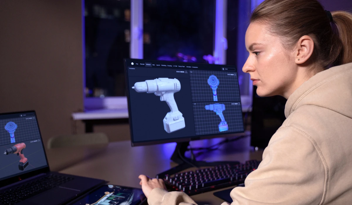 A woman focused on her computer, creating a 3D model on the screen in a bright, modern workspace.
