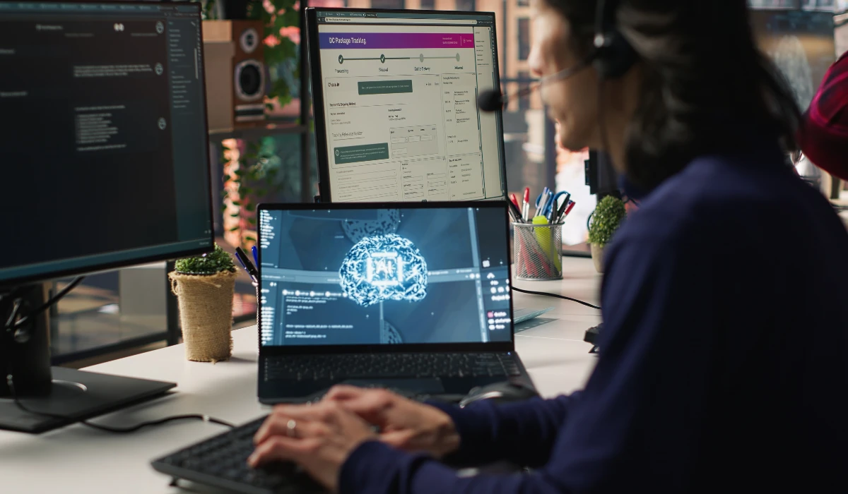 A woman focused on her work, using a computer with two monitors for increased productivity.