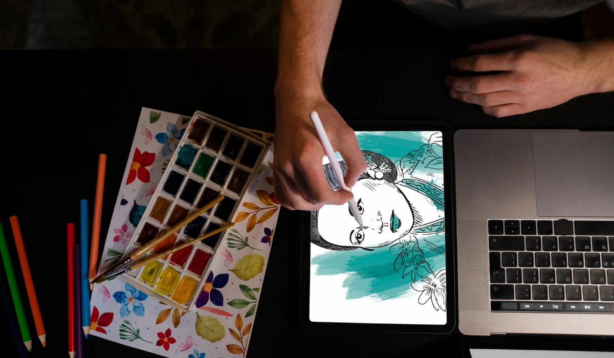 A person uses a pen to draw on a laptop screen, focused on their creative work.