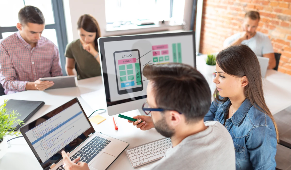 A diverse group of people collaborating on a computer in a bright office space.