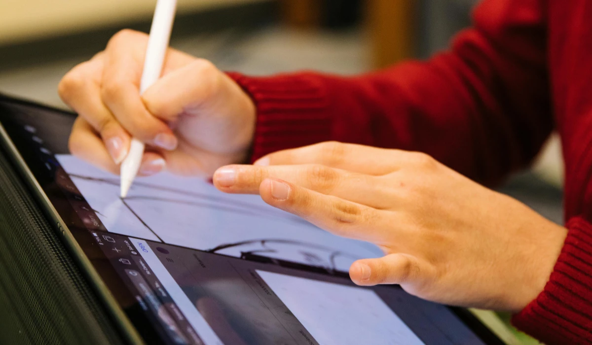 A person drawing on a tablet computer, focused on creating digital art with a stylus.