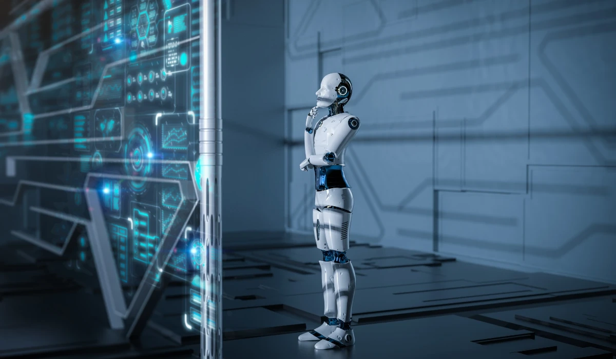 A robot stands in front of a computer screen, showcasing a blend of technology and innovation.