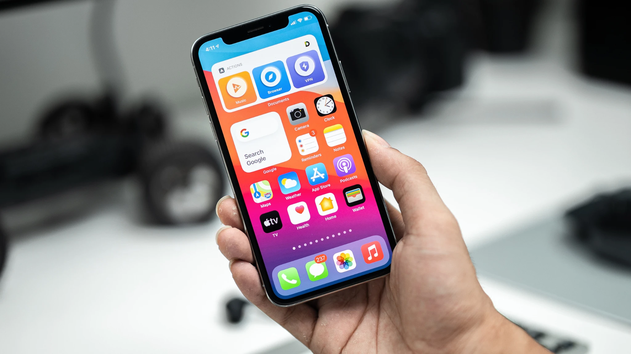 A person holding an iPhone displaying the App Store on the screen, showcasing various app icons and options.