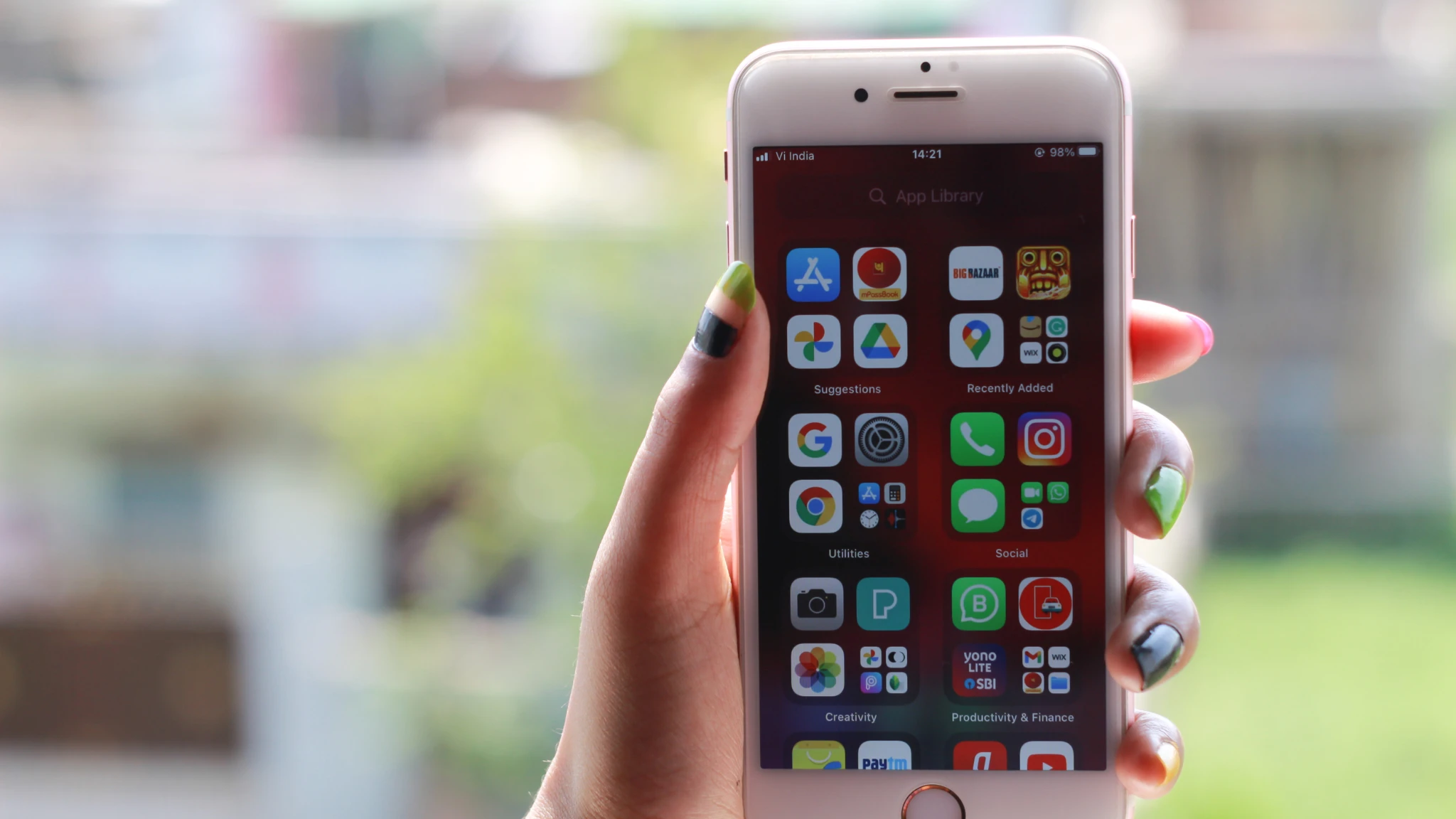 A person holding an iPhone displaying a variety of colorful app icons on the screen.