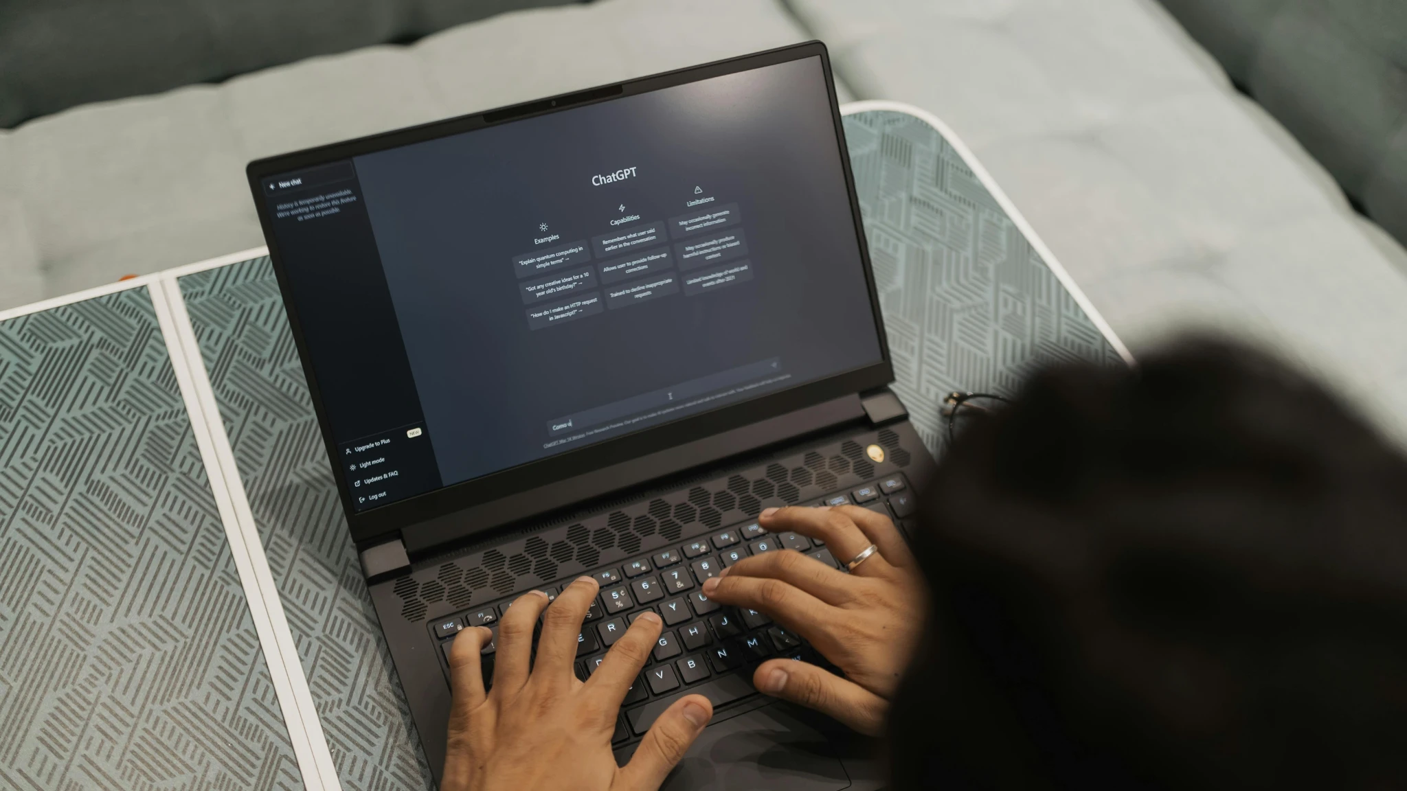 A person focused on typing on a laptop, with hands on the keyboard and a bright screen in front of them.