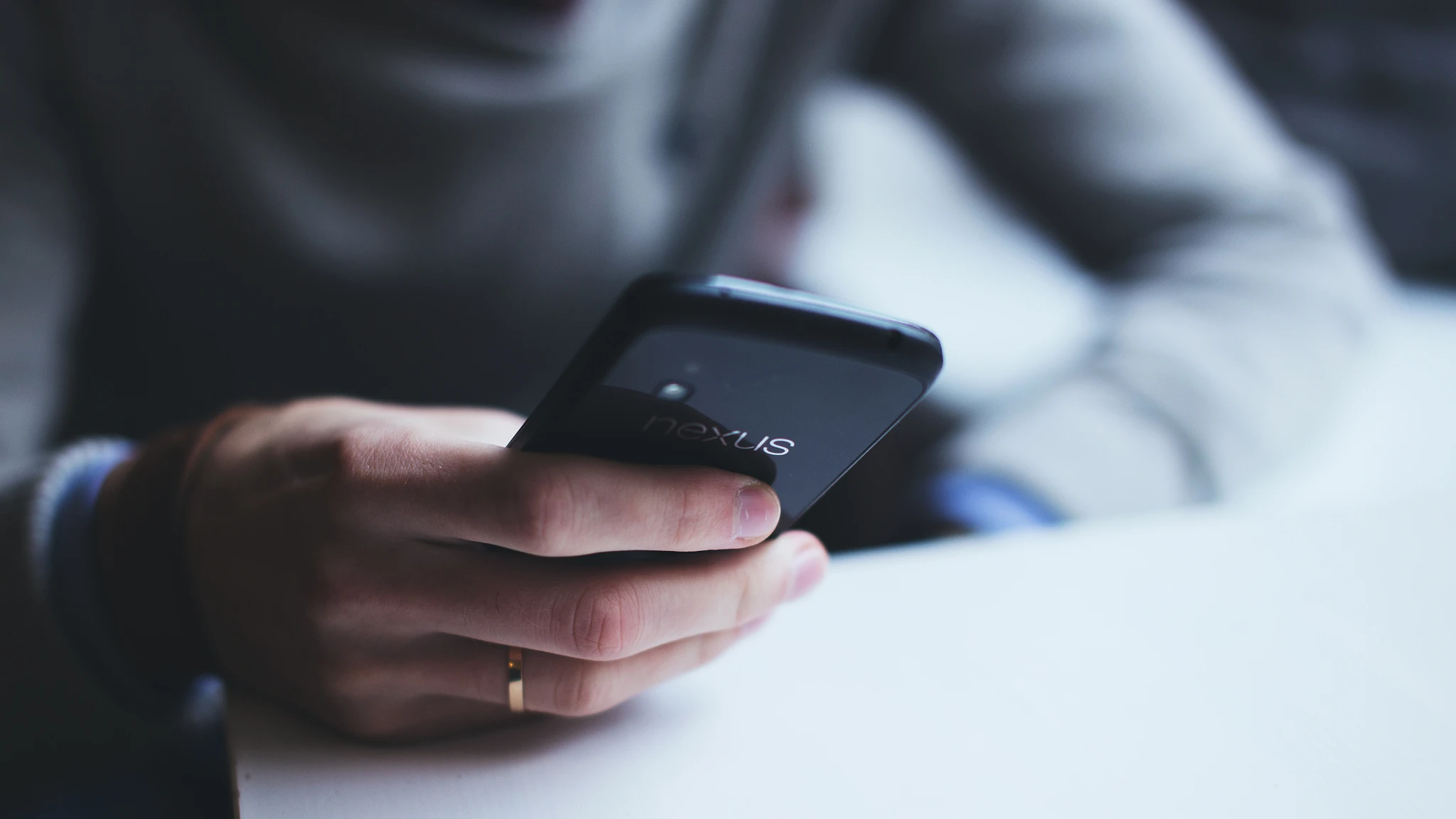 A person holding a cell phone in their hand, looking at the screen with a focused expression.