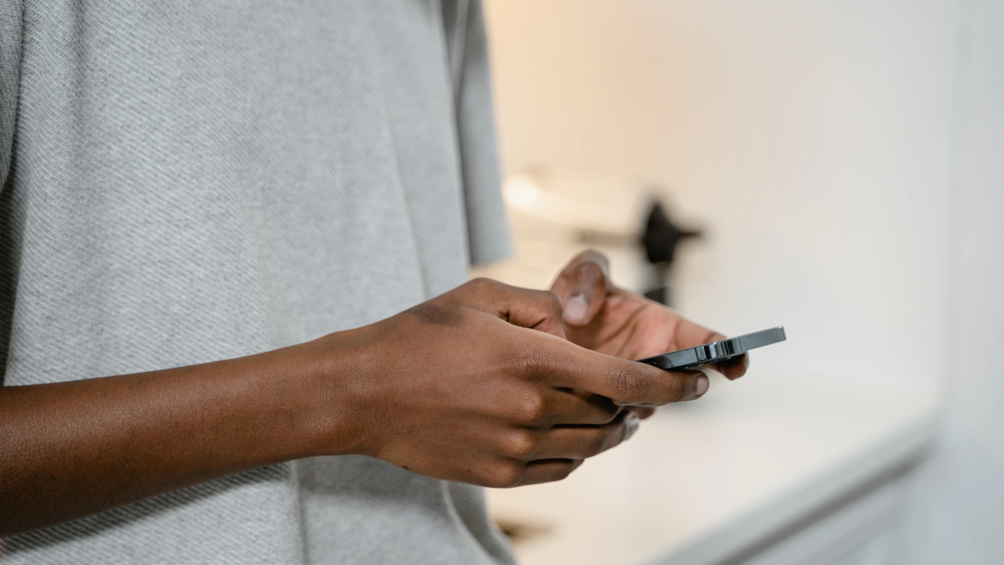A person holding a cell phone in their hand, looking at the screen with a focused expression.