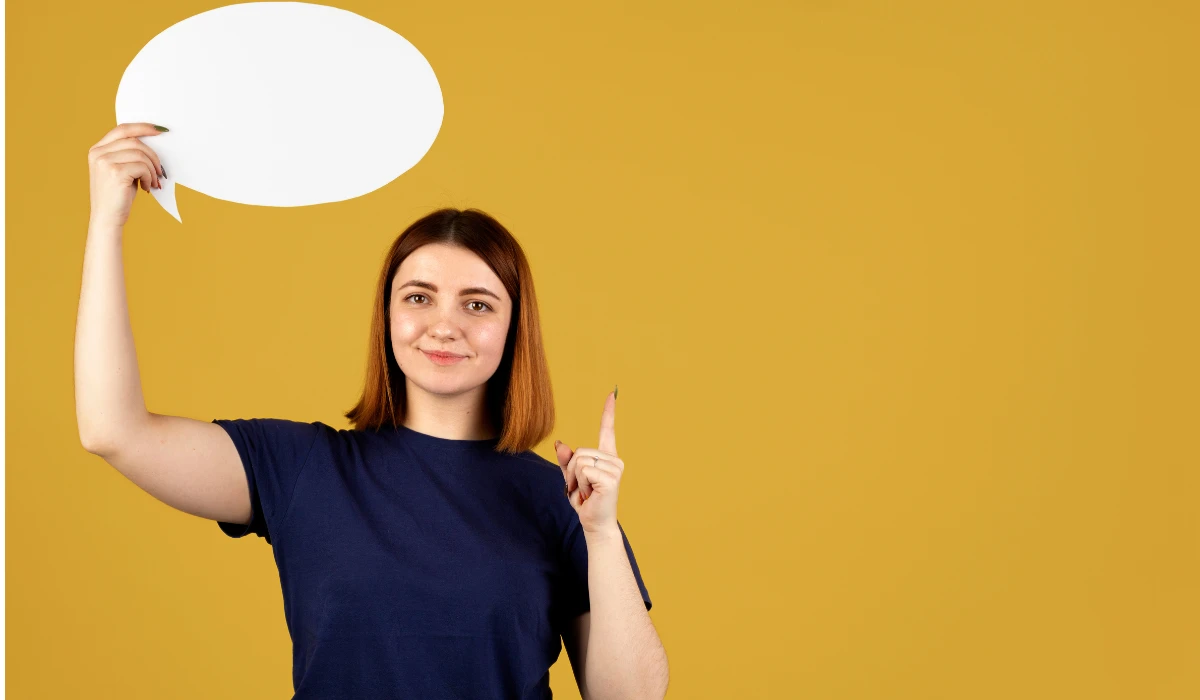 A woman smiles while holding a speech bubble against a bright yellow background.