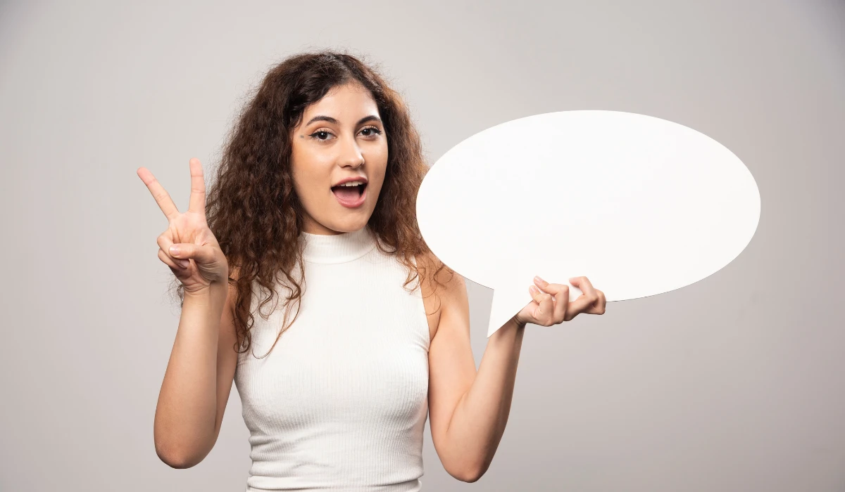 A woman holds a speech bubble with her hand, representing dialogue and sharing ideas.