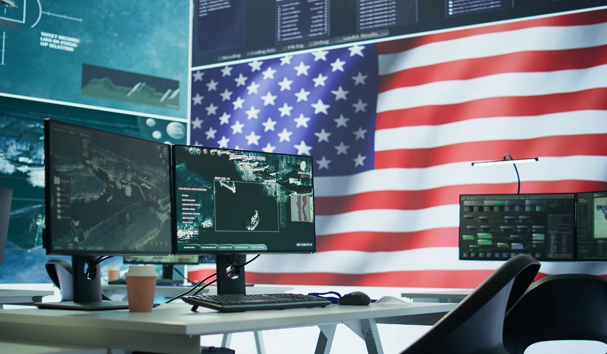Image illustrating cybersecurity with a hacker silhouette in front of the American flag, highlighting national defense.