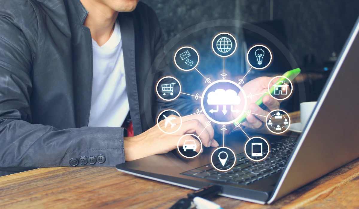 A man using a laptop with colorful icons on the screen, appearing concentrated on his task.