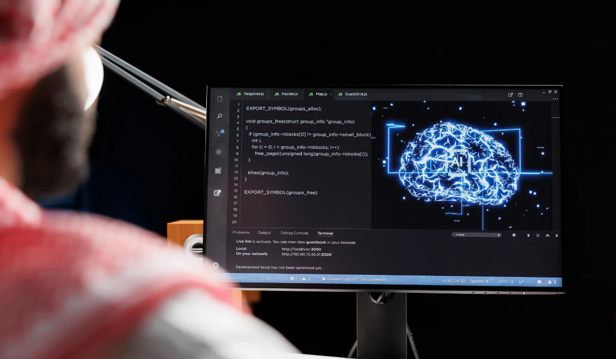 A man with a headscarf is observing a computer screen, appearing concentrated on the information displayed.