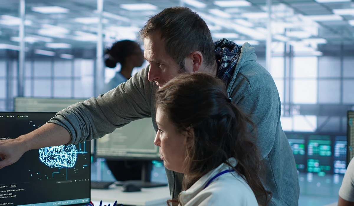 A man and woman engaged in teamwork, analyzing information on a computer screen.