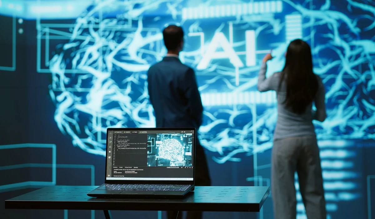 Two people standing together, looking at a computer screen, engaged in discussion or collaboration.
