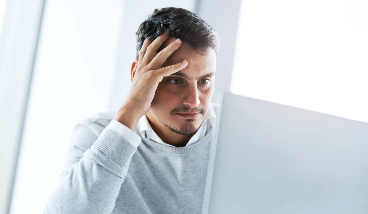 A man looks at a computer screen, concentrating on the information displayed.