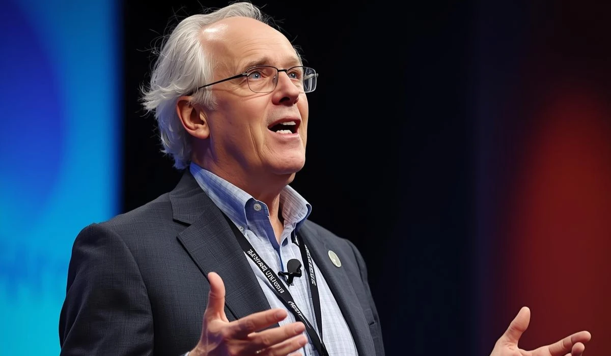 A man in glasses and a suit is speaking confidently at a podium.
